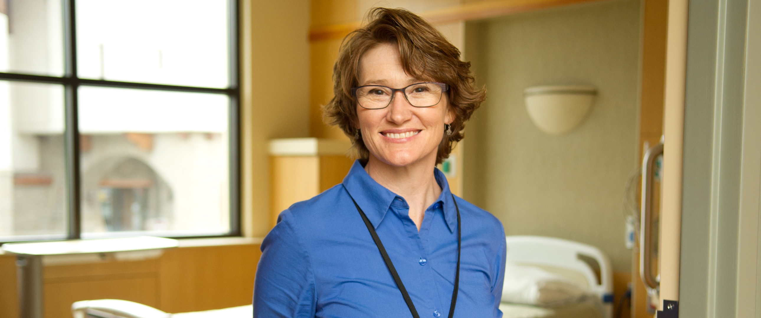 Pt Shannon Hafermann stands in an acute care room.