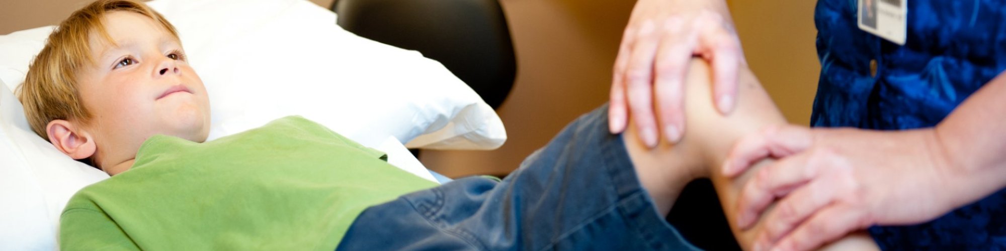 A nurse examines a pediatric patient's knee.