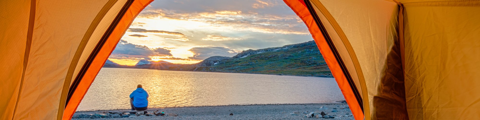 A backpacker rests near a mountain lake.