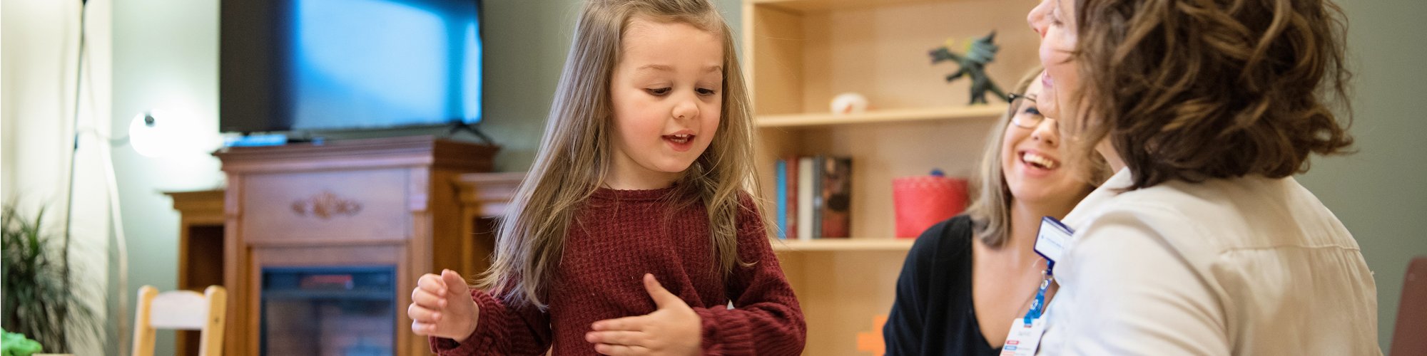 A child signs "please" as she learns communication skills in therapy.